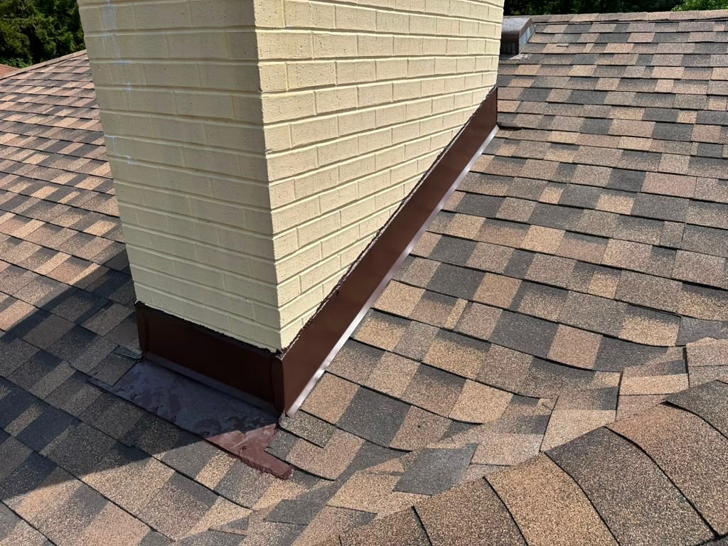 New chimney flashing installed against a brick chimney