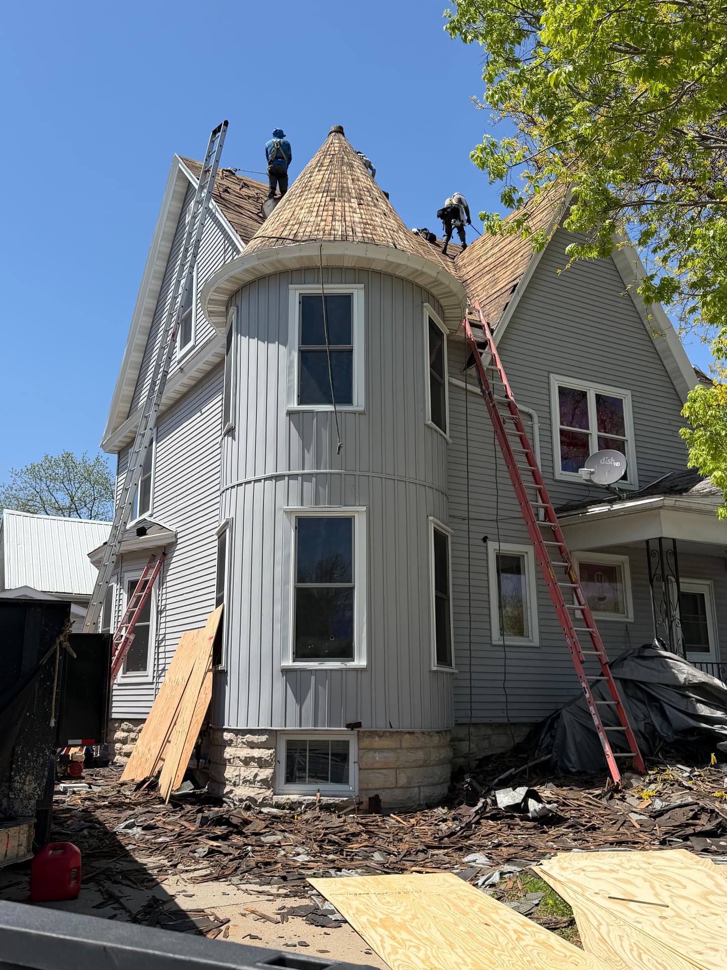 Crew tearing off old cedar shakes on a Victorian home with turret